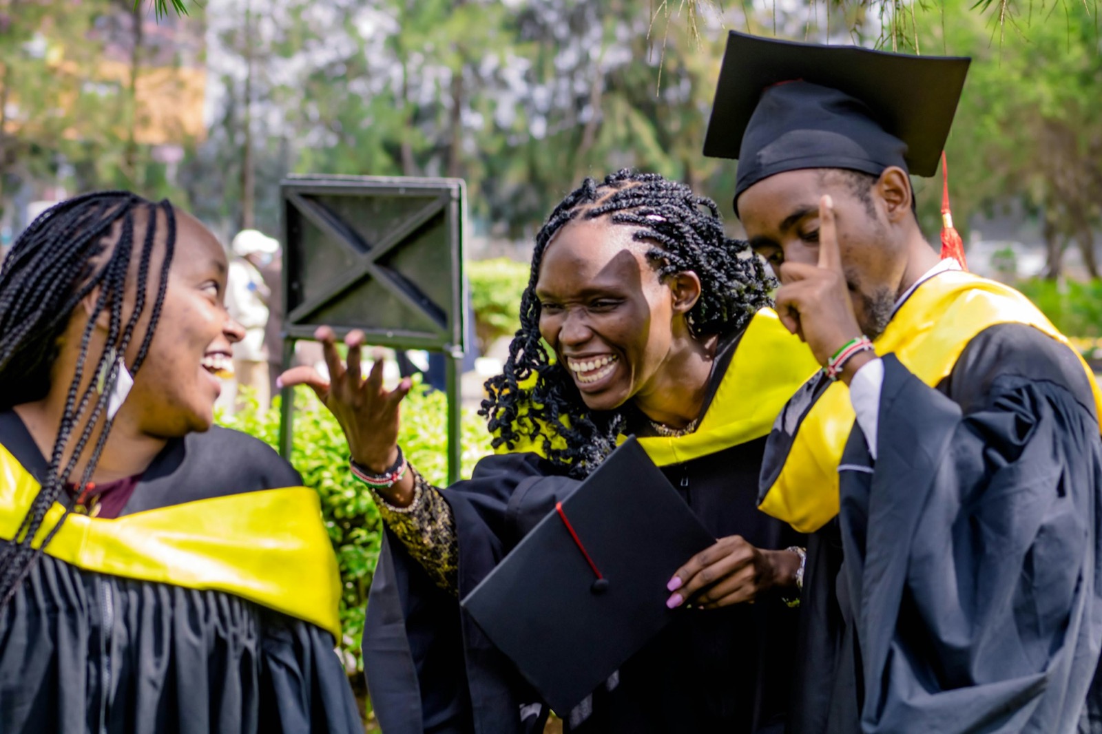Jeunes diplômés africains riant ensemble sur un campus, en toge de graduation